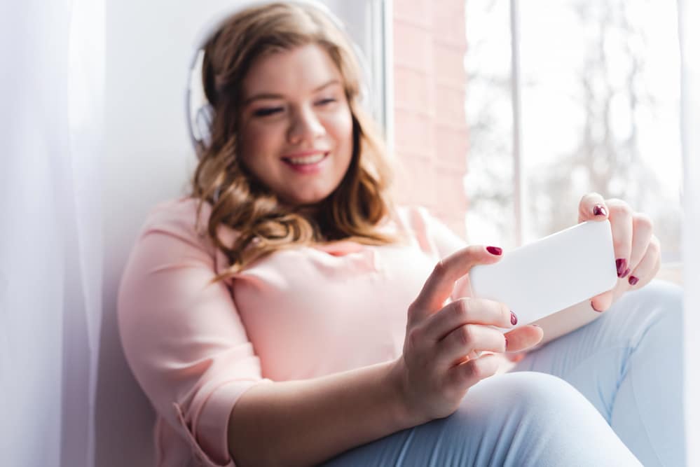 Young woman wearing headphones and watching video on phone